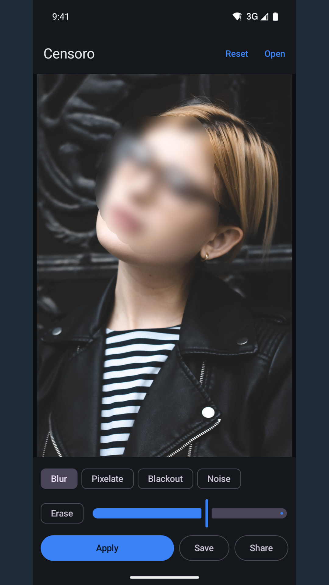 A portrait with the face blurred; hair, leather jacket and the street behind stay sharp.